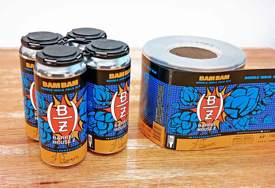 A four pack of Bam Bam Ale with labels from Barrel House Z alongside a roll of bam bam ale labels